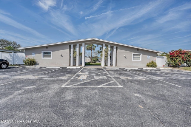 view of building exterior featuring uncovered parking and fence