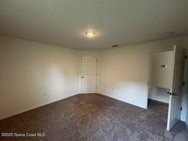 unfurnished bedroom featuring a textured ceiling, carpet flooring, visible vents, and baseboards