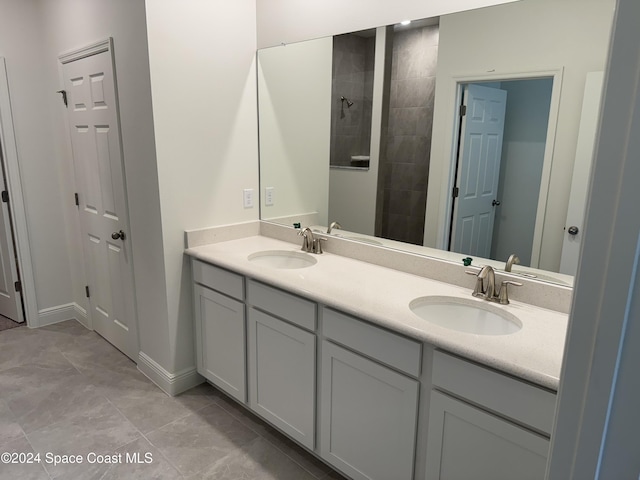 bathroom featuring tile patterned flooring, vanity, and a tile shower