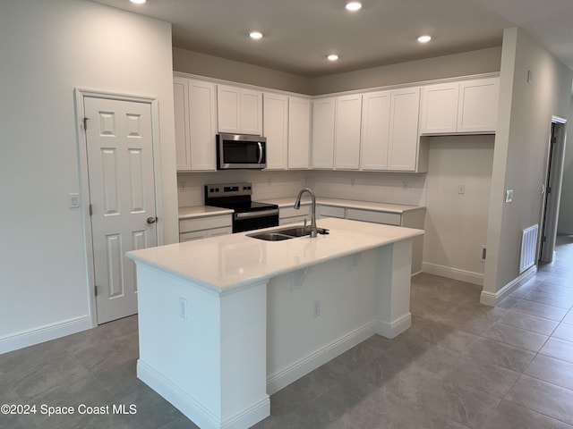 kitchen with backsplash, a kitchen island with sink, sink, appliances with stainless steel finishes, and white cabinetry