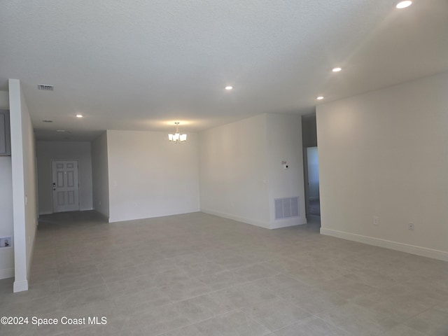 empty room featuring a textured ceiling and a notable chandelier