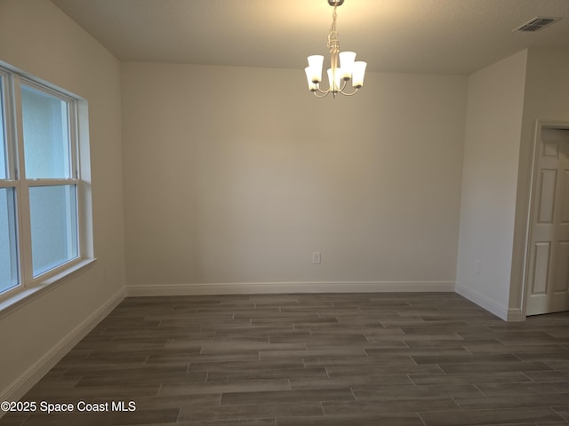 unfurnished room featuring a chandelier