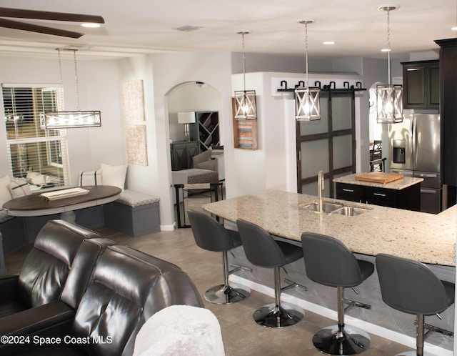 680 Easton Forest Cir SE, Palm Bay, FL 32909 - kitchen featuring stainless steel fridge with ice dispenser, a sink, a center island, a kitchen bar, and light stone countertops