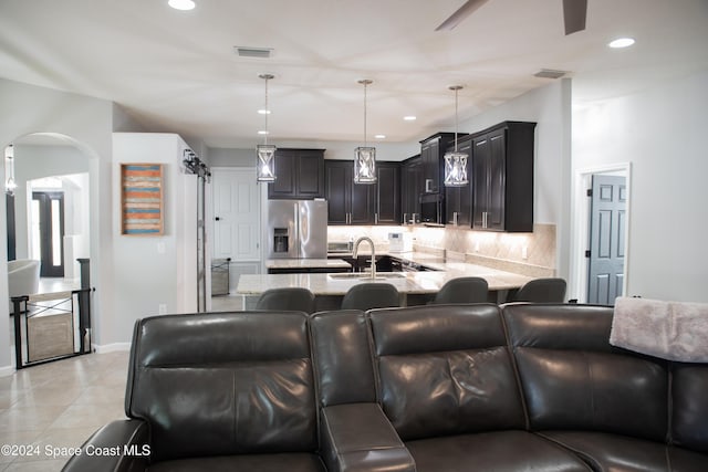 680 Easton Forest Cir SE, Palm Bay, FL 32909 - kitchen featuring stainless steel fridge with ice dispenser, a sink, tasteful backsplash, a peninsula, and light stone countertops