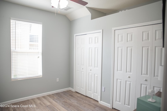680 Easton Forest Cir SE, Palm Bay, FL 32909 - unfurnished bedroom with multiple closets, wood finished floors, vaulted ceiling, baseboards, and a ceiling fan