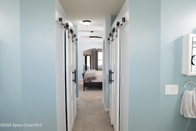 hallway with a barn door and light tile patterned flooring