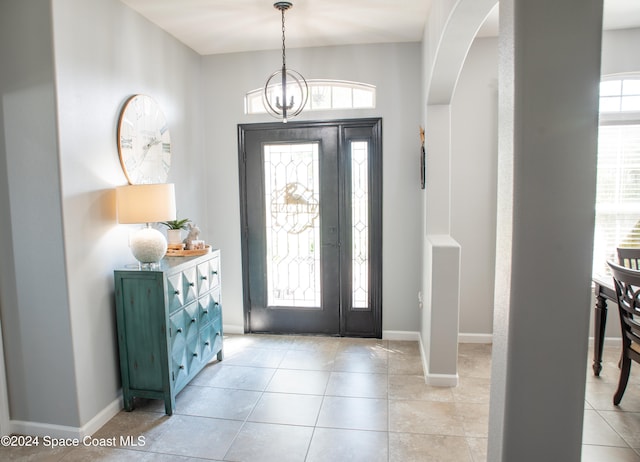 tiled entrance foyer with a chandelier