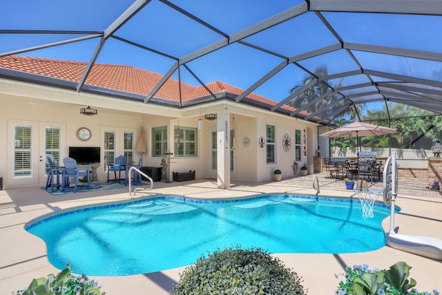 view of swimming pool featuring glass enclosure and a patio