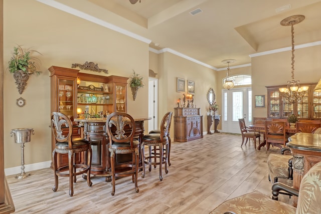 dining area featuring light hardwood / wood-style floors, ornamental molding, and an inviting chandelier