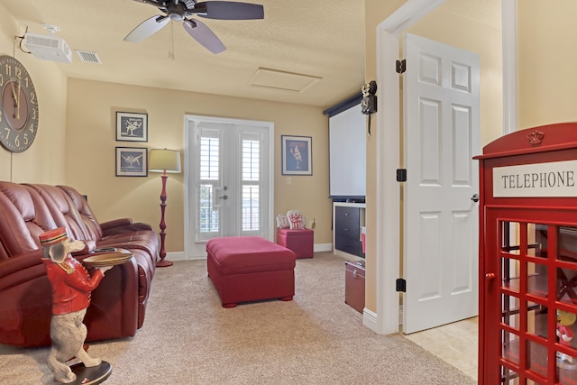 living room with ceiling fan, light colored carpet, and a textured ceiling