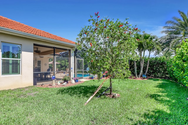 view of yard featuring glass enclosure and ceiling fan