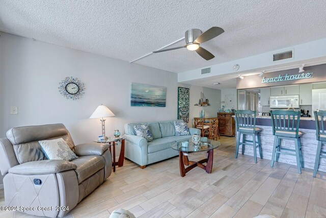 living room with a textured ceiling and ceiling fan