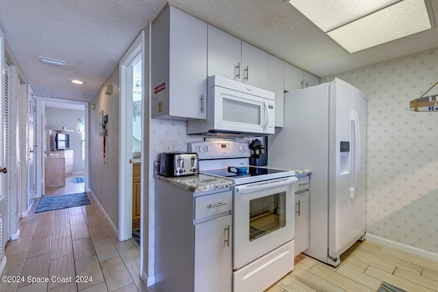 kitchen featuring white cabinetry, light tile patterned floors, a textured ceiling, and white appliances