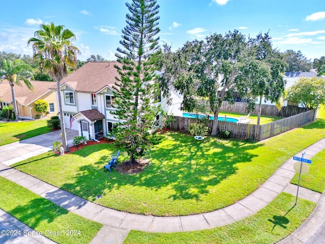 exterior space featuring driveway, a front lawn, an attached garage, and fence