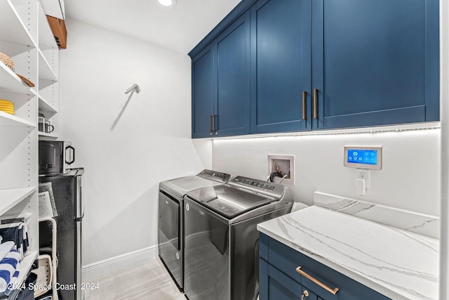 clothes washing area featuring independent washer and dryer and cabinets