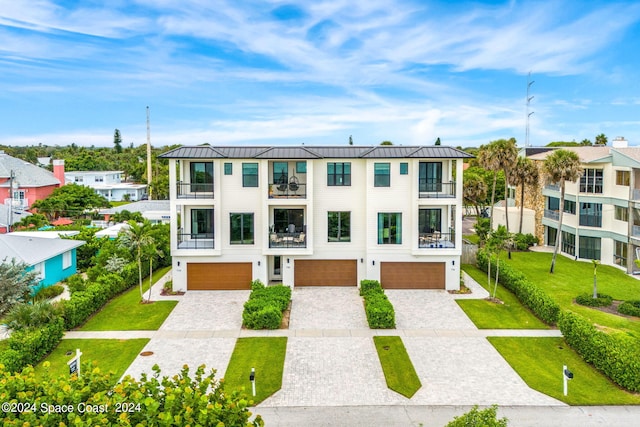 view of front of property featuring a garage, a balcony, and a front yard