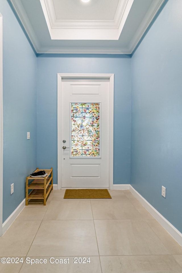 entryway with a tray ceiling, light tile patterned flooring, and ornamental molding