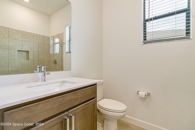 bathroom featuring toilet, a tile shower, and vanity