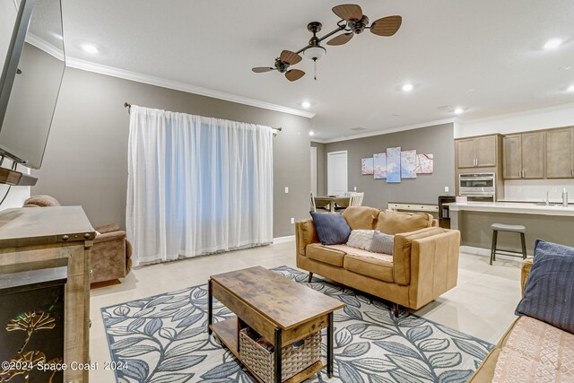 tiled living room with ceiling fan, sink, and crown molding