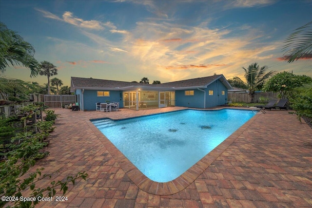 pool at dusk featuring a patio area