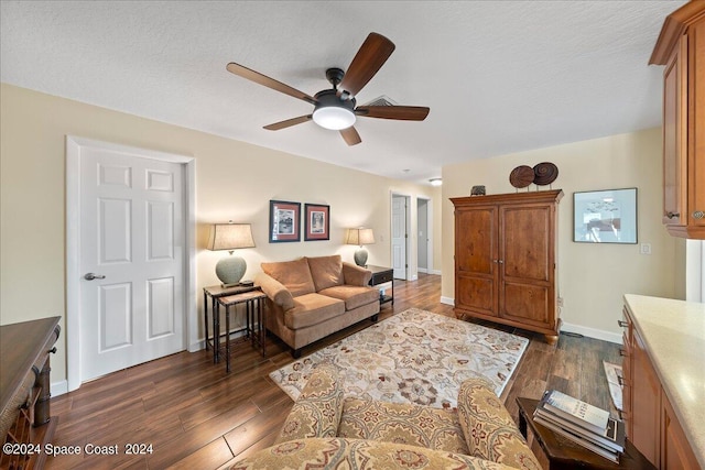 living room with ceiling fan, dark wood-type flooring, and a textured ceiling