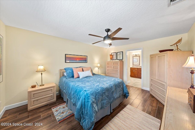 bedroom with ensuite bath, ceiling fan, dark wood-type flooring, and a textured ceiling