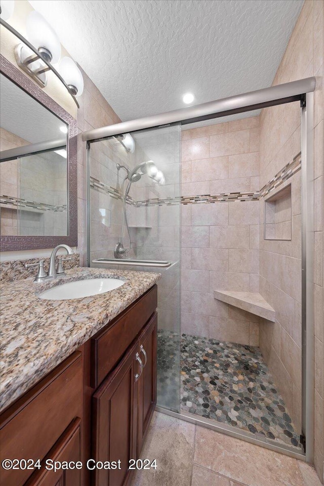 bathroom featuring vanity, a shower with shower door, and a textured ceiling