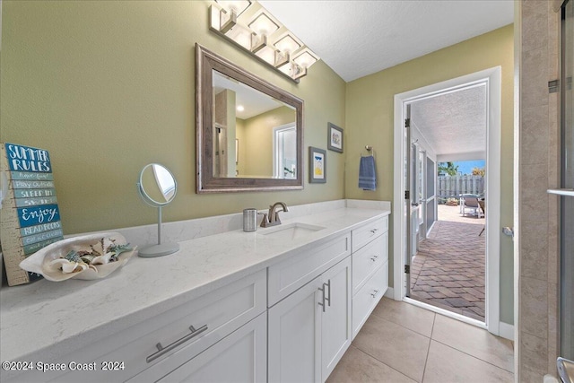 bathroom with tile patterned floors, vanity, and a textured ceiling