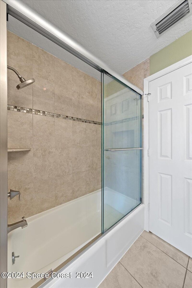 bathroom with shower / bath combination with glass door, tile patterned flooring, and a textured ceiling