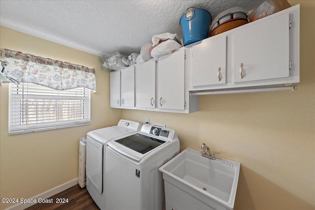 laundry area with cabinets, a textured ceiling, washer and clothes dryer, dark wood-type flooring, and sink