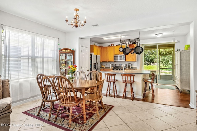 dining room with a textured ceiling, sink, light wood-type flooring, and a chandelier