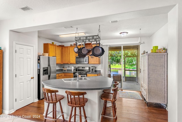 kitchen featuring dark hardwood / wood-style flooring, stainless steel appliances, a kitchen breakfast bar, and a textured ceiling