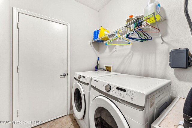 clothes washing area with washing machine and dryer and light tile patterned floors