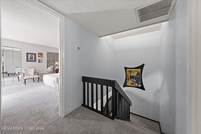 stairs with a textured ceiling and carpet flooring