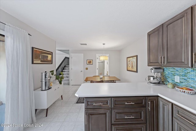 kitchen with light tile patterned flooring, kitchen peninsula, pendant lighting, and decorative backsplash