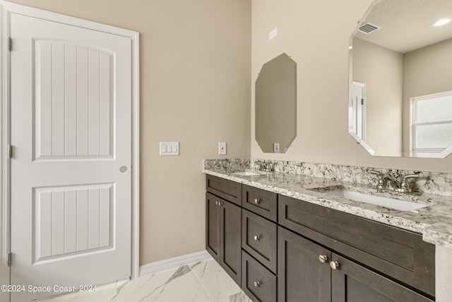 bathroom featuring double vanity, marble finish floor, baseboards, and a sink