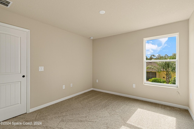 carpeted spare room with baseboards, visible vents, and a textured ceiling