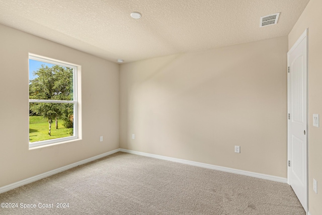 unfurnished room with carpet, a textured ceiling, visible vents, and baseboards