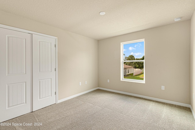 unfurnished bedroom featuring carpet, a textured ceiling, baseboards, and a closet