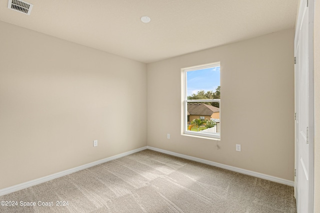 unfurnished room with light colored carpet, visible vents, and baseboards