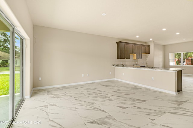 kitchen featuring light stone counters, recessed lighting, baseboards, open floor plan, and marble finish floor