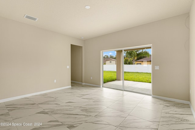 empty room featuring marble finish floor, baseboards, and a textured ceiling