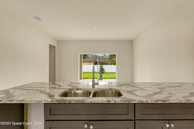 kitchen featuring sink, a textured ceiling, and light stone countertops