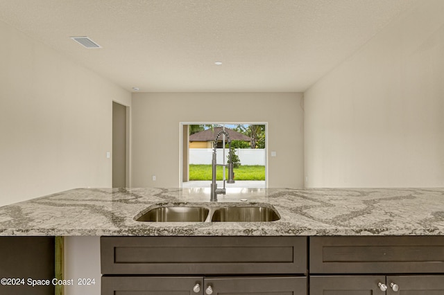 kitchen featuring visible vents, a sink, and light stone countertops