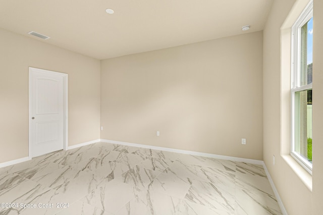 spare room featuring marble finish floor, baseboards, and visible vents