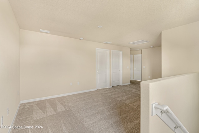 unfurnished room with light carpet and a textured ceiling