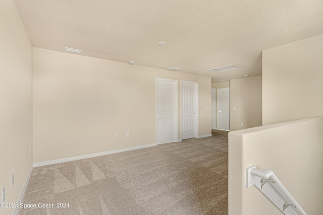 carpeted spare room with a textured ceiling and baseboards