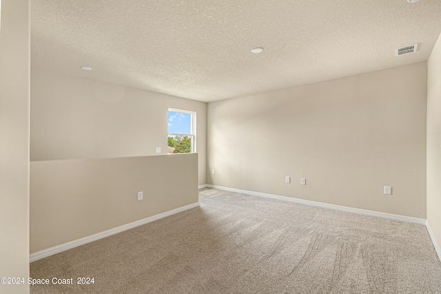 carpeted spare room featuring a textured ceiling