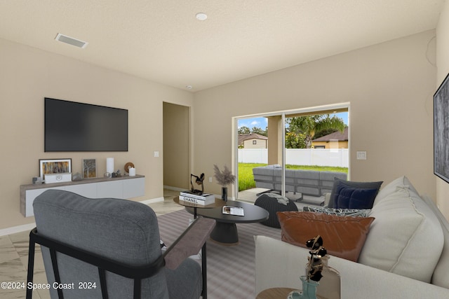 living area featuring visible vents, a textured ceiling, and baseboards