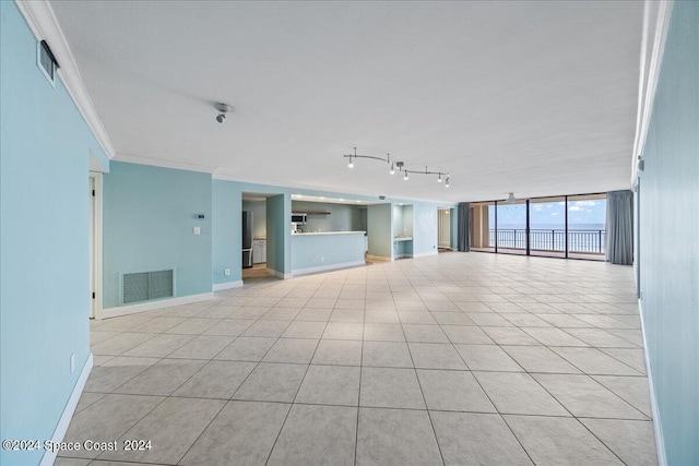 unfurnished living room with light tile patterned floors, baseboards, visible vents, and crown molding